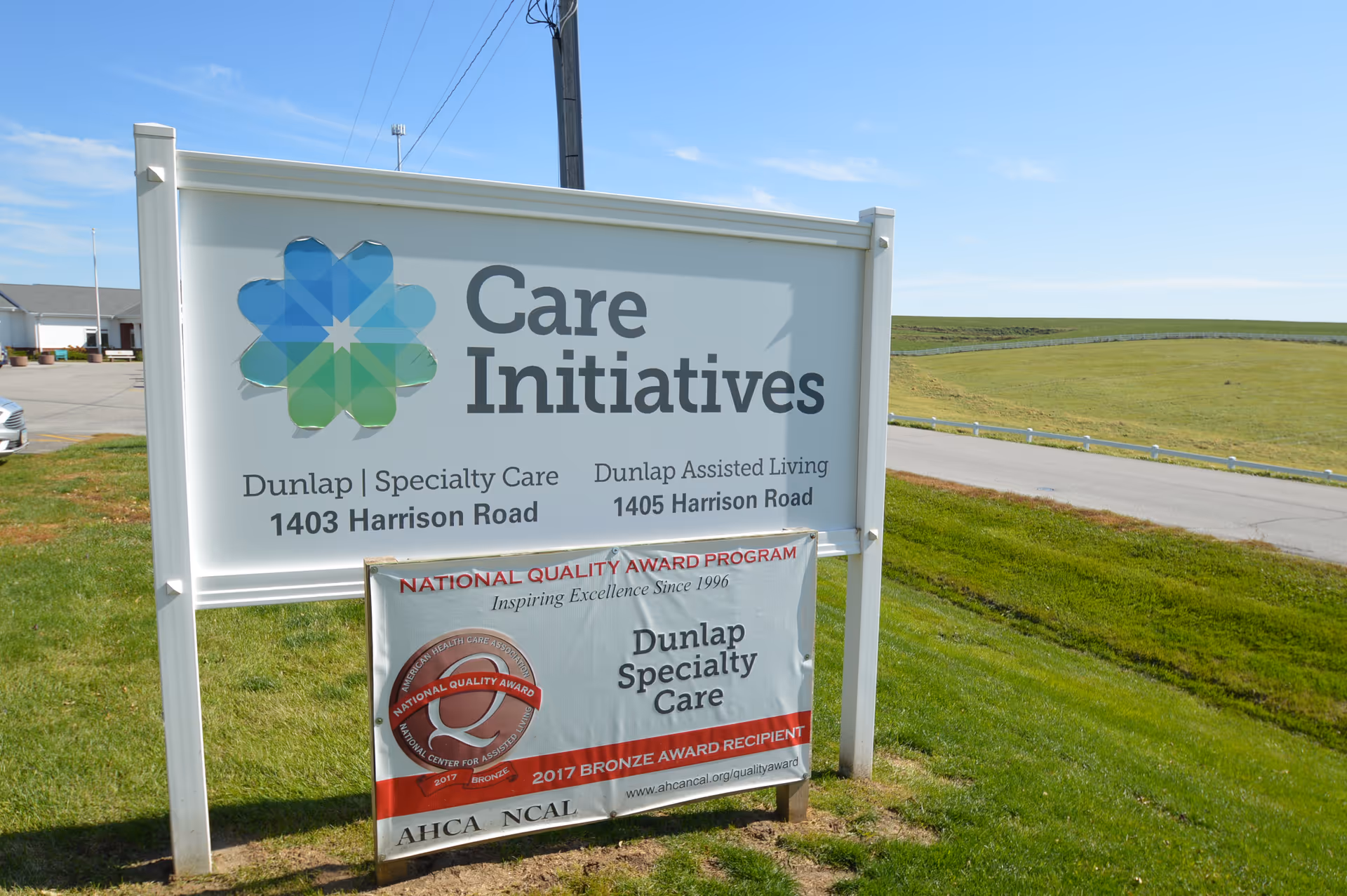 Freestanding roadside sign for Care Initiatives and Dunlap Specialty Care with address and award banner on a grassy lawn.