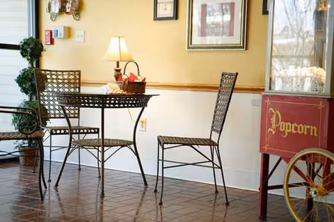 Metal bistro table and two chairs sit in a cozy dining area with a popcorn cart.