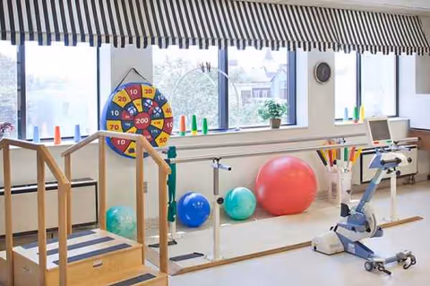 Indoor rehabilitation gym area with exercise balls, a stationary bike, and therapy equipment.