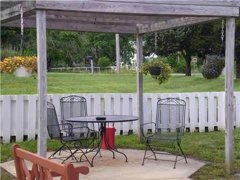 Outdoor patio with metal chairs around a round table under a wooden pergola