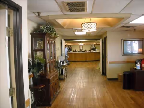 Long hallway inside a nursing home with a reception desk at the far end.