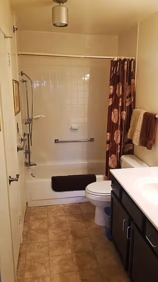 Bathroom with a bathtub and shower, toilet, sink vanity, patterned shower curtain, and towel rack.