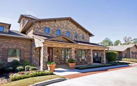 Exterior view of Heritage Oaks Assisted Living and Memory Care building with stone facade and porch.