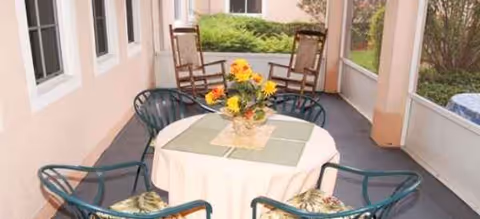Outdoor covered patio with a round table, several chairs, and a flower centerpiece.