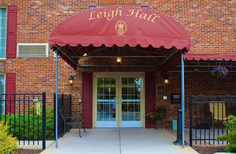 Brick building exterior with red canopy over double glass doors reading Leigh Hall