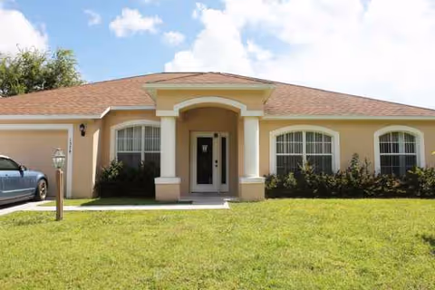 Single-story beige senior living facility with arched entrance and well-kept front lawn.