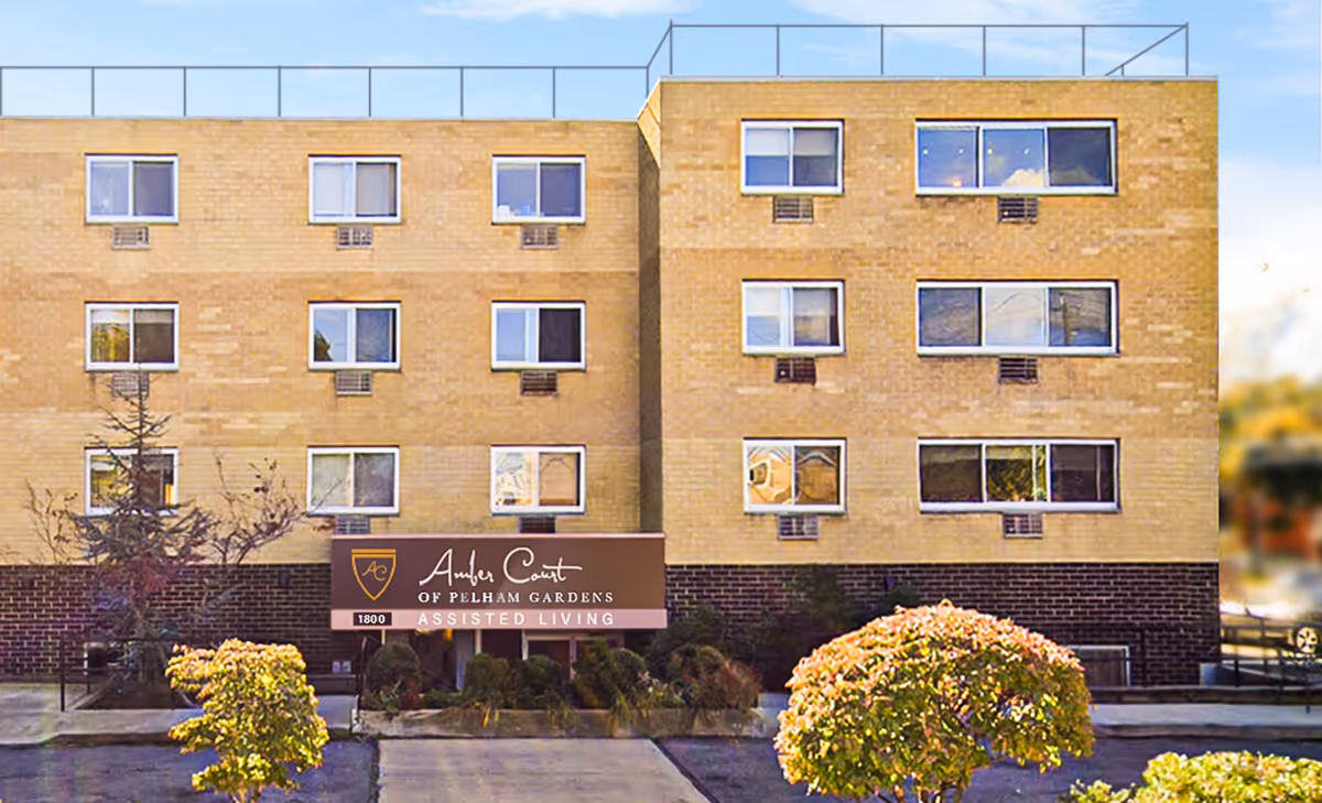 Front exterior view of Amber Court of Pelham Gardens assisted living facility, a multi-story brick building with several windows and a sign above the entrance displaying the facility's name.