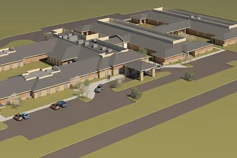 A 3D architectural rendering of Bourbonnais Grove Assisted Living & Memory Care facility showing a single-story building with multiple wings, a covered entrance with cars parked nearby, surrounding landscaping, and driveways.