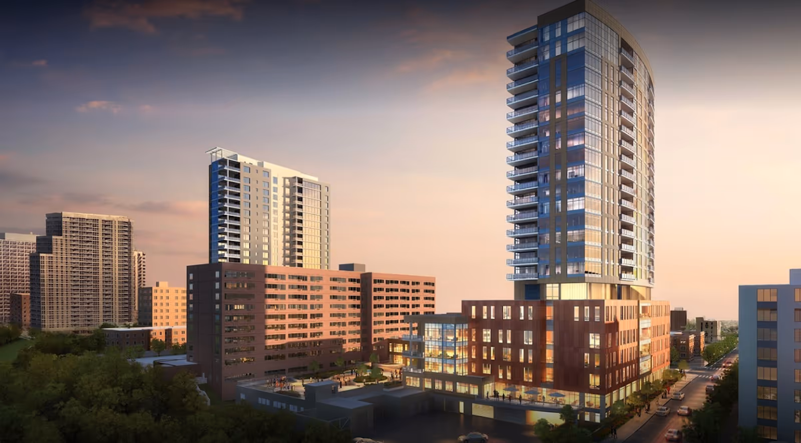 Modern high-rise residential complex with a tall glass tower and adjoining mid-rise buildings at sunset.