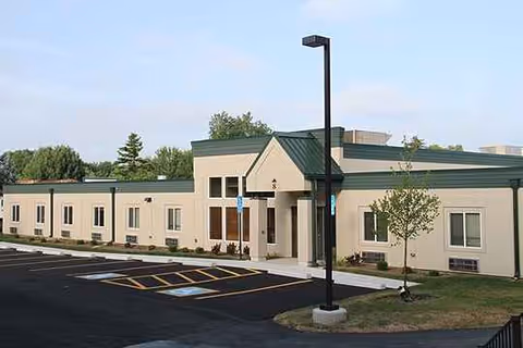 Exterior view of a single-story senior living building with a parking lot and entrance.