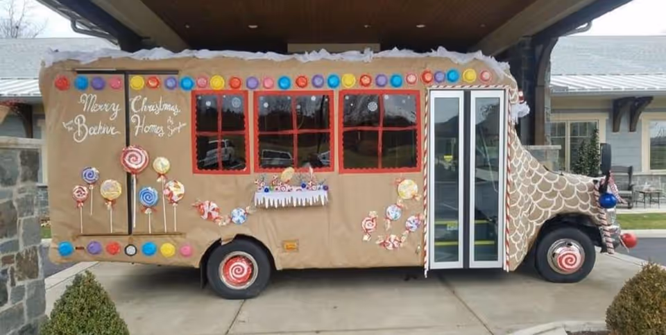 Candy-themed bus decorated with lollipops and lights parked outside BeeHive Homes of Springboro.