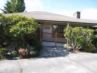 Front exterior of Happy Days AFH II with a porch and surrounding shrubs.