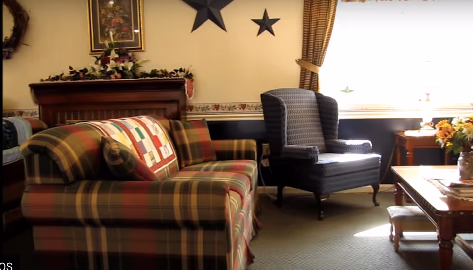 Cozy living room with a plaid sofa, wingback armchair, coffee table and decorative wall stars by a bright window.