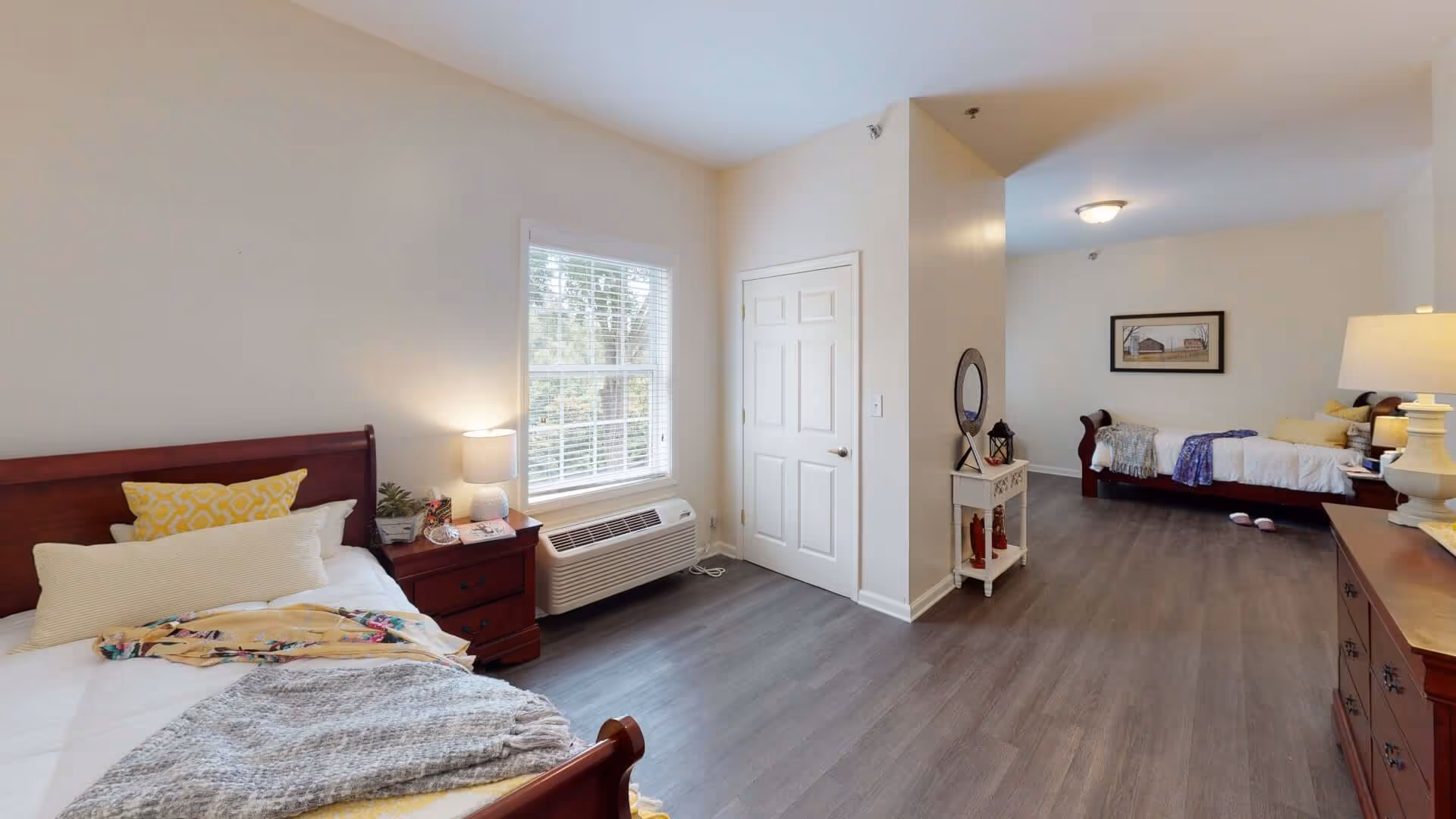 Bright, spacious bedroom with two single beds, wooden furniture, a window, and wood-look flooring.