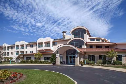 Sunny day view of Garden Villas North senior living facility exterior with arches.