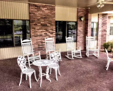 White metal outdoor furniture with a round table and chairs on a brick patio.