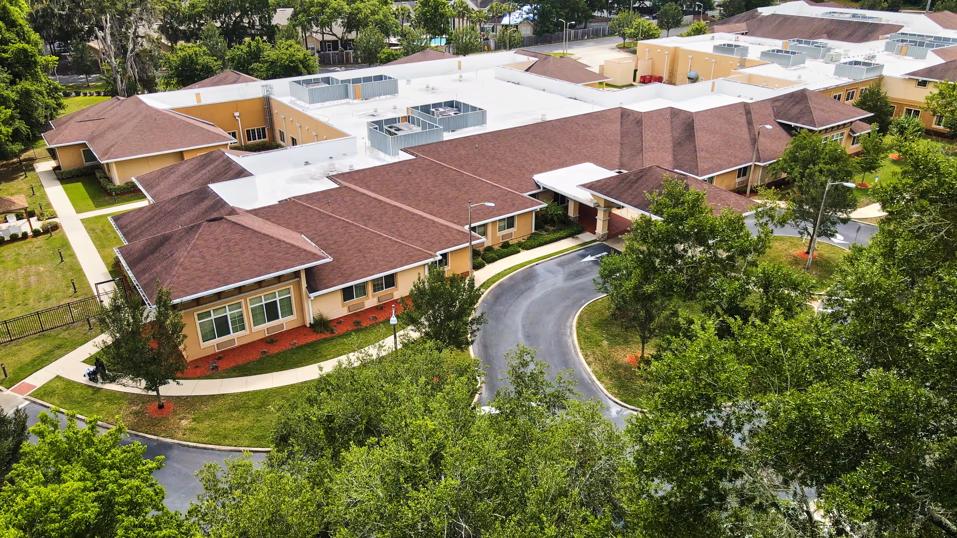 Aerial view of Plaza Health and Rehab Center showing connected wings, a curved driveway, and landscaped grounds.