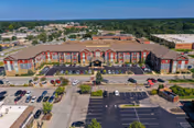 Aerial front view of a three-story senior living building with a landscaped entrance and parking lot.