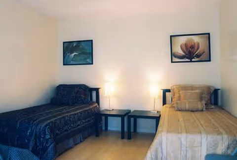 Two single beds with bedside tables and lamps in a shared bedroom.