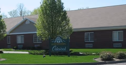 Exterior view of Oakwood Health Campus building with a green lawn, a tree, and a sign displaying the facility's name in front of the building.