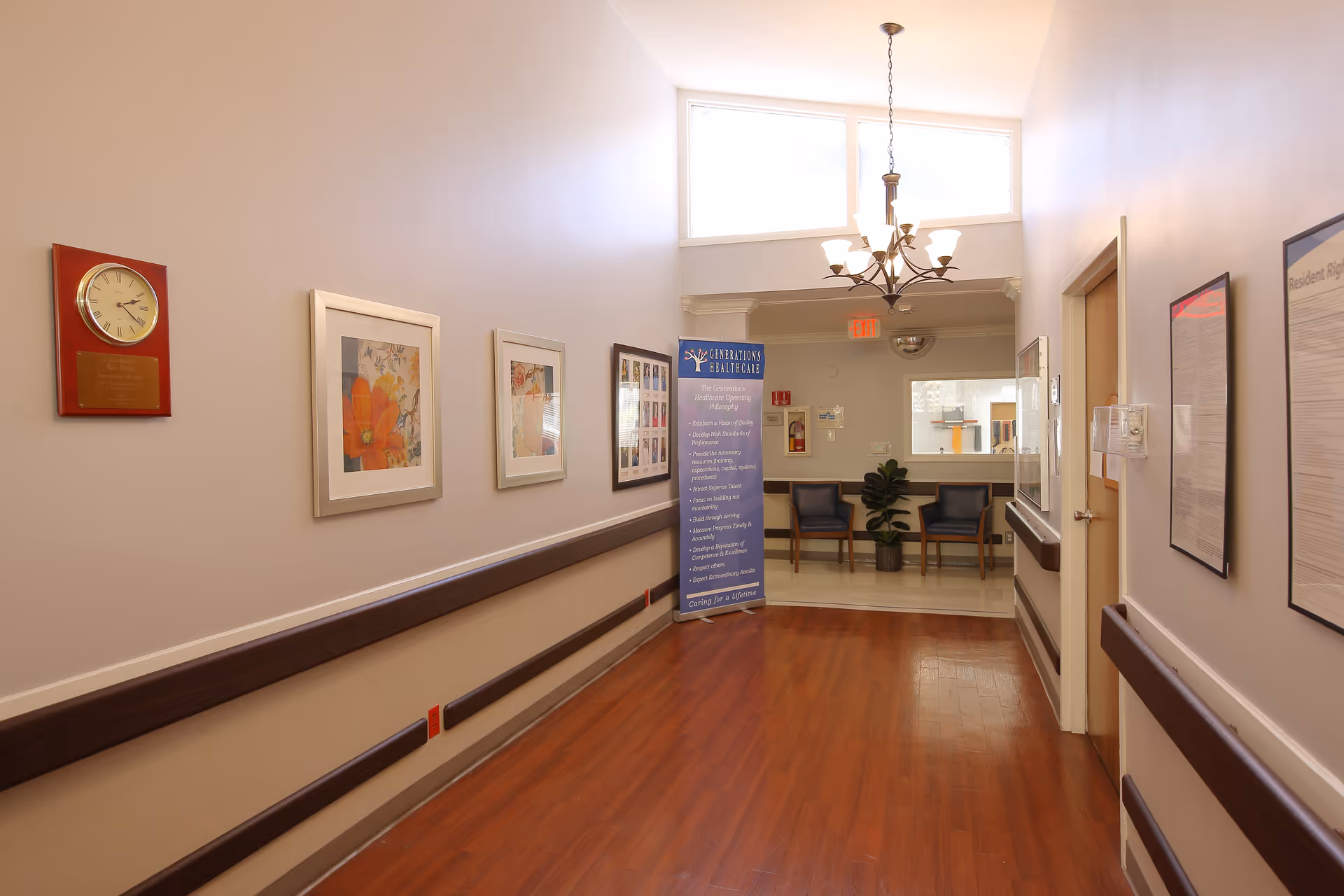 A hallway in a senior living facility with artwork on the walls and seating areas.