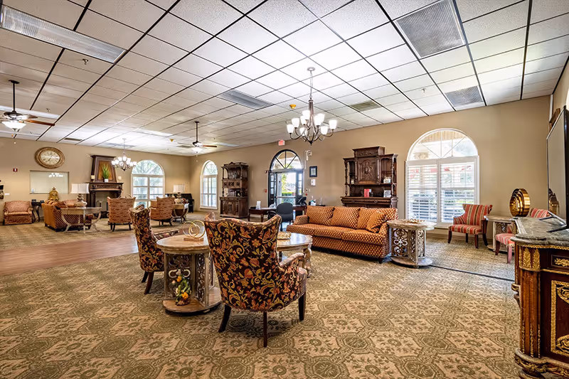 A spacious common area in a senior living facility with comfortable seating and decorative furnishings.