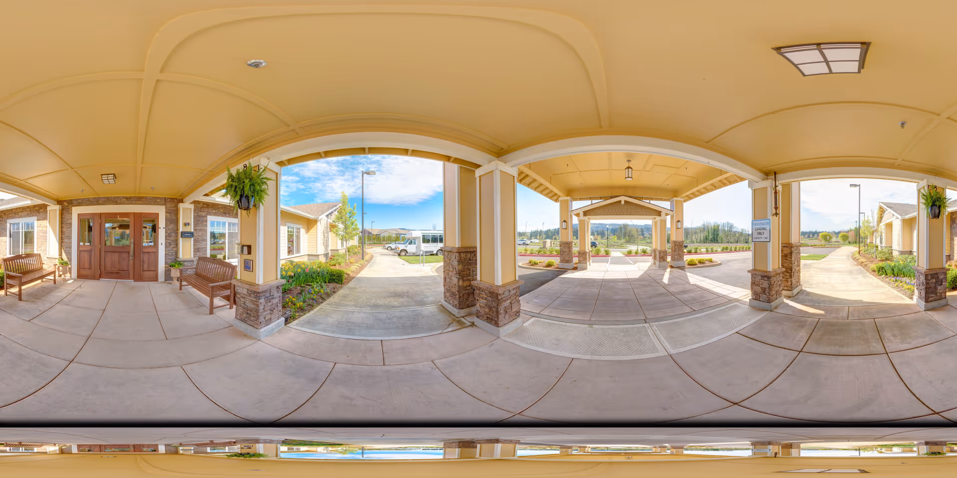 Covered porte-cochere entrance to a memory care residence with benches, columns, and a drive-up walkway.