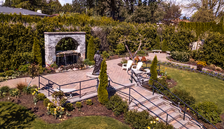 Well-maintained outdoor courtyard with a paved patio, fountain, statue, seating, and landscaped garden paths.