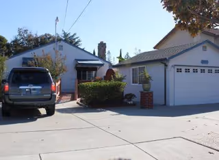Exterior view of Bed of Roses Residential Care Home with parked SUV, driveway, and shrubs.