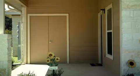 Exterior view of Terraces at Cibolo entrance with double doors and sunflowers on the porch.