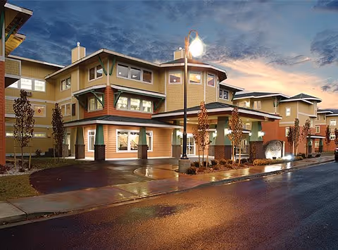 Exterior view of South Hill Village senior living facility at dusk.