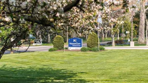 Well-manicured lawn with a facility sign and blooming trees.