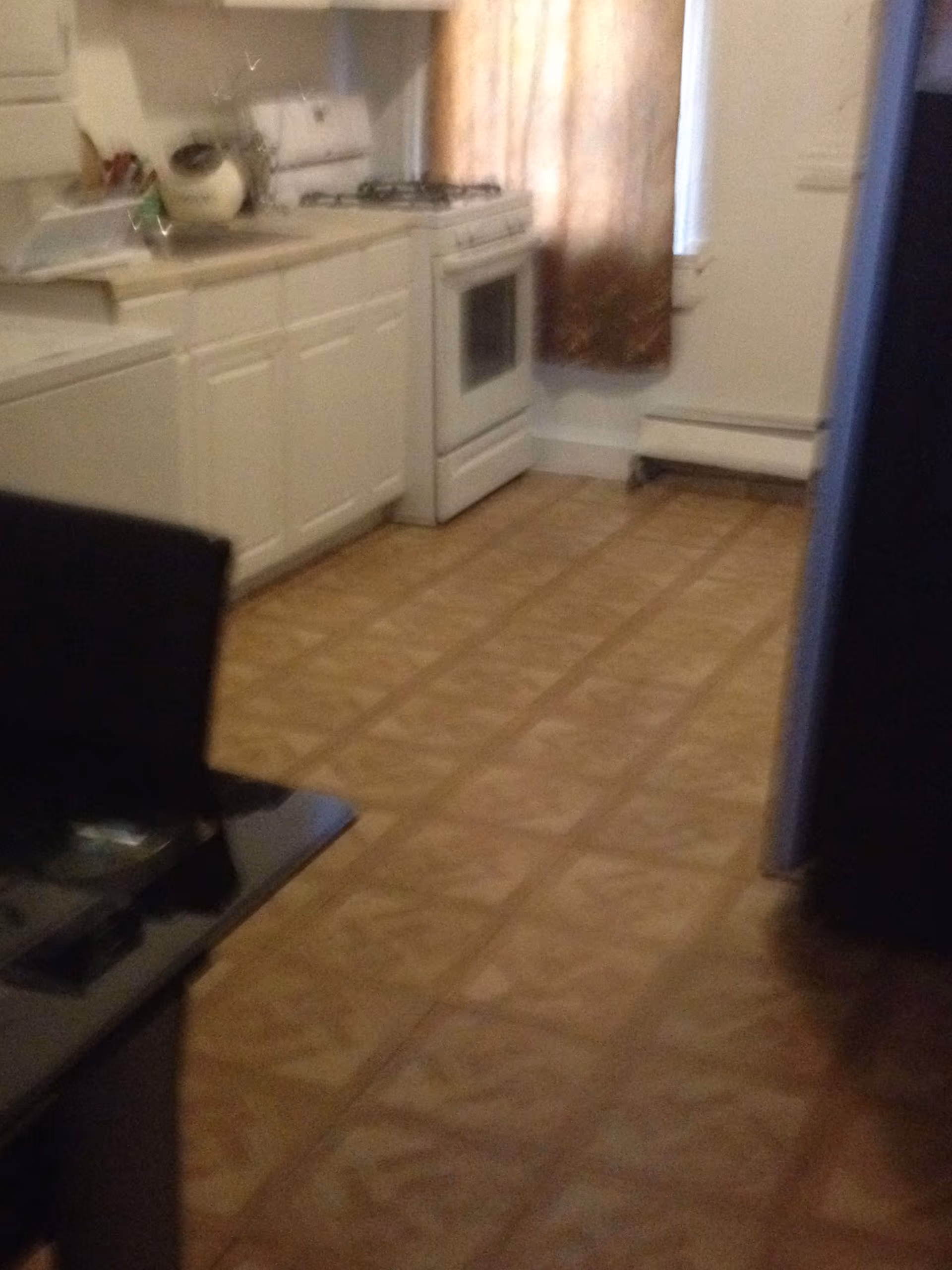 Small kitchen with white cabinets, a gas stove, countertop appliances, and patterned linoleum floor.