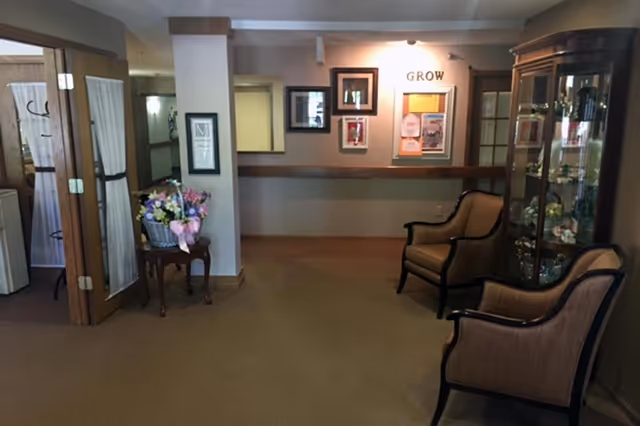 Senior living interior lounge with seating, flowers, and bulletin boards.