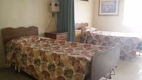 Two twin beds with floral quilts in a shared senior living bedroom.