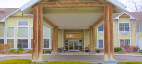 Front entrance of a yellow senior living facility with a covered entry