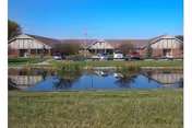 Exterior view of Cardinal Care Strategies facility with a pond and parking lot