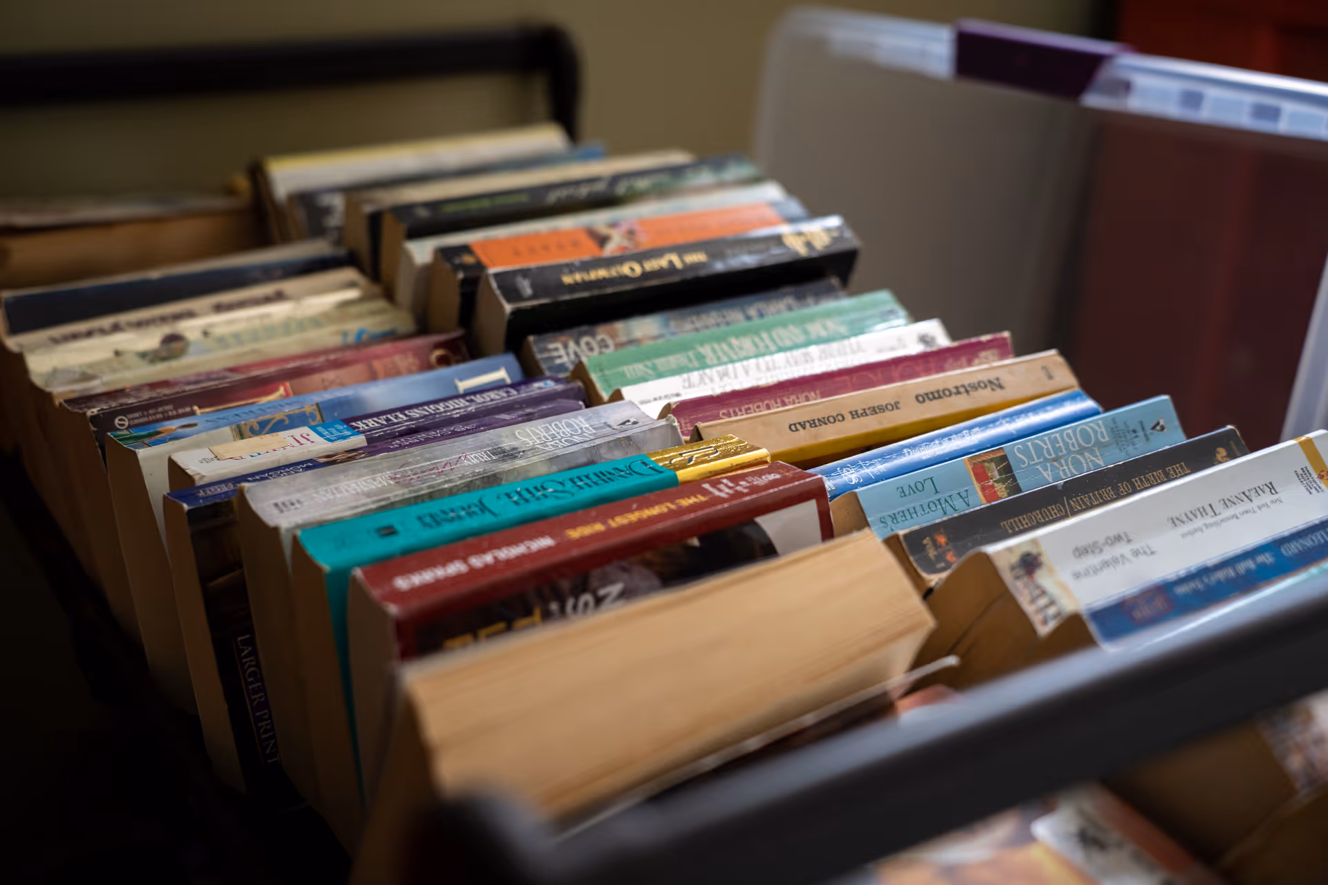 A trolley filled with rows of paperback books arranged spine-up in an indoor setting.
