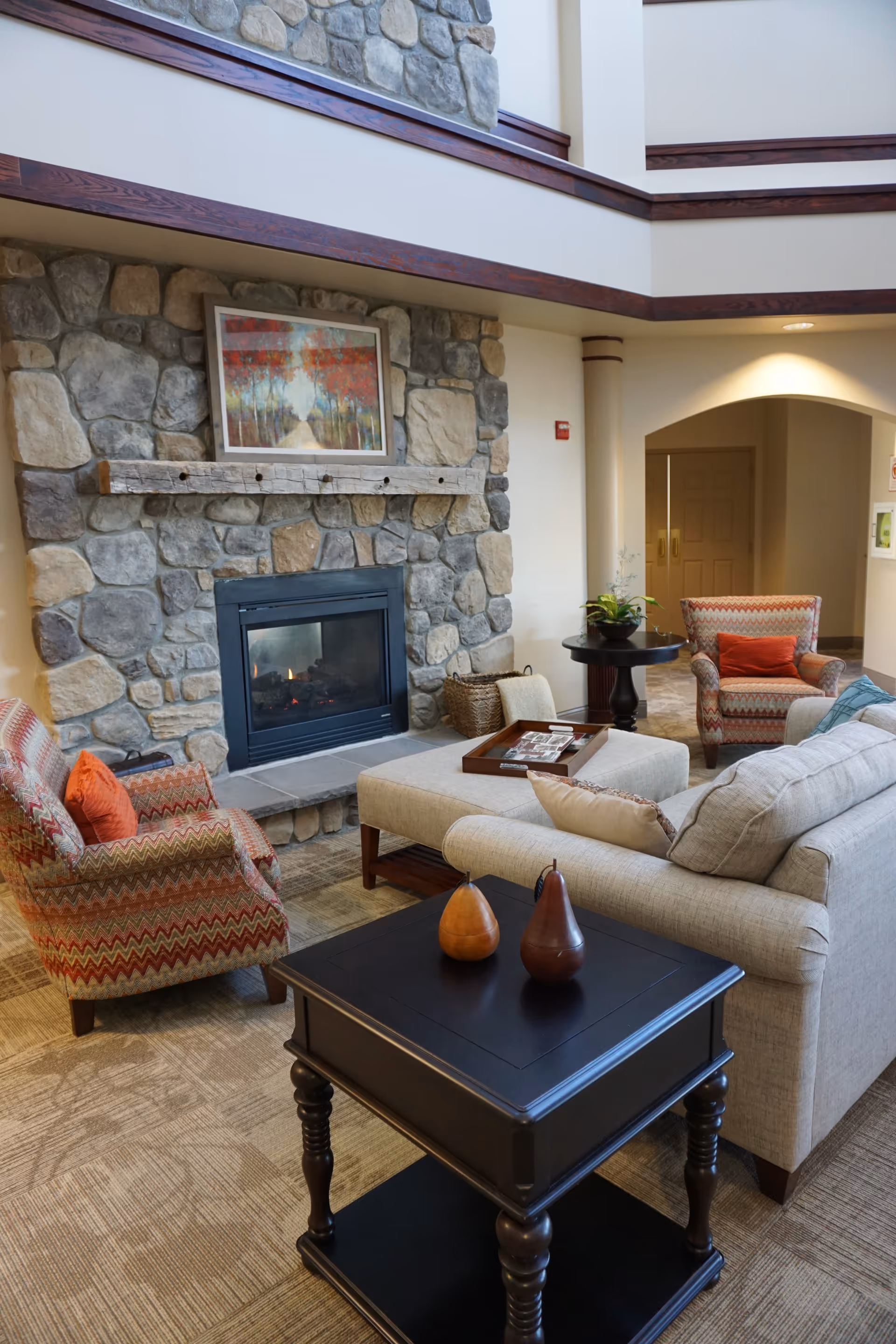 Lobby-style living room with a stone fireplace, sofas and armchairs arranged around coffee tables.