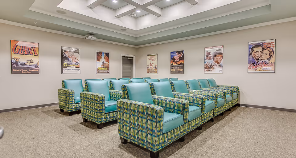 Rows of teal and patterned armchairs arranged theater-style in a screening room decorated with vintage movie posters.