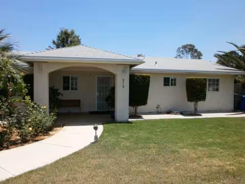 Exterior view of a single-story Woodland Borden Care facility with walkway and lawn.