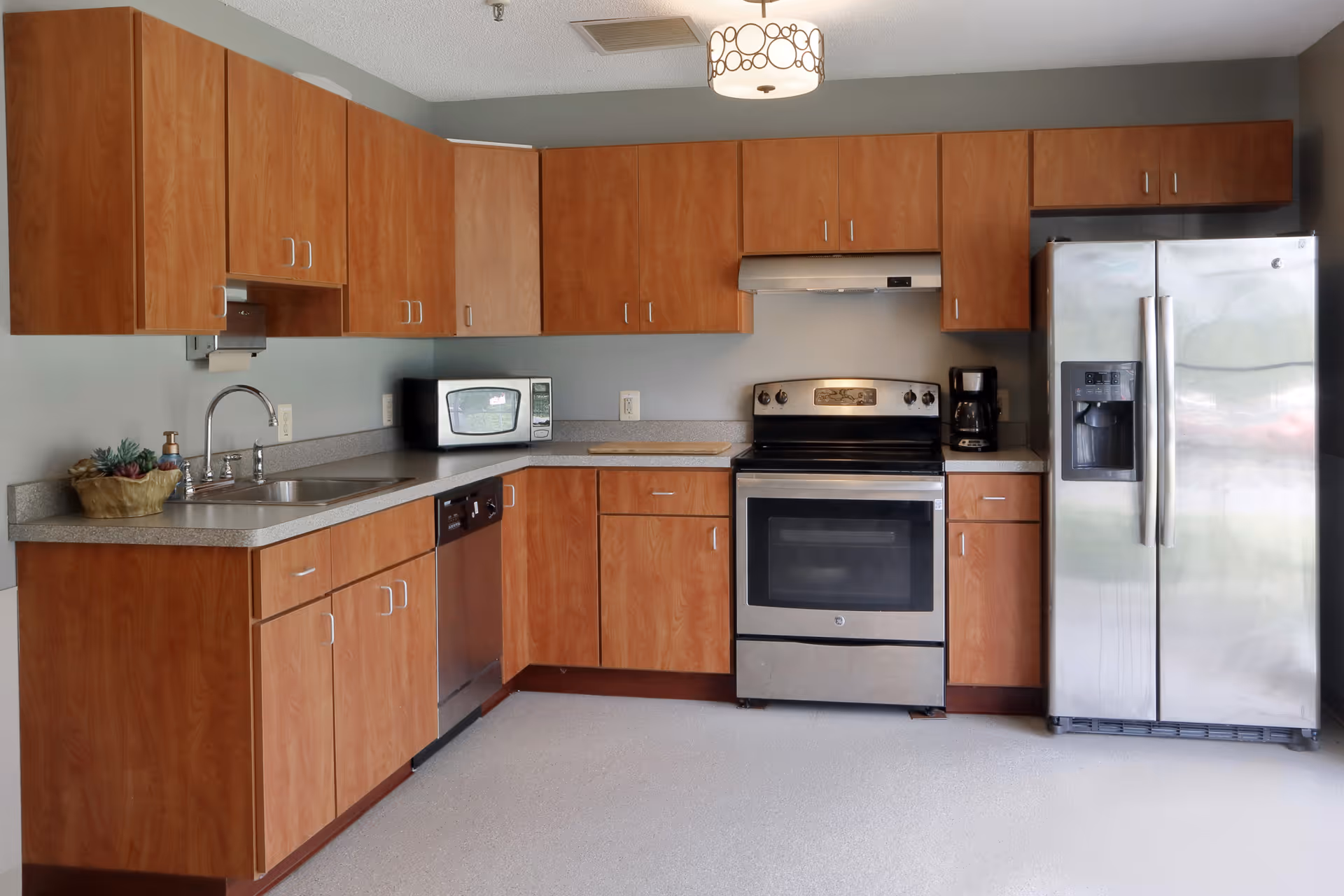 Kitchen with wood cabinets, stainless steel refrigerator and oven, sink, microwave, and countertop appliances.