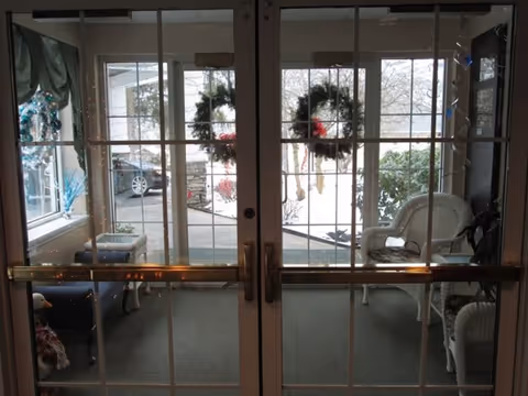 Glass double doors with holiday wreaths leading from a small furnished foyer to the outside.