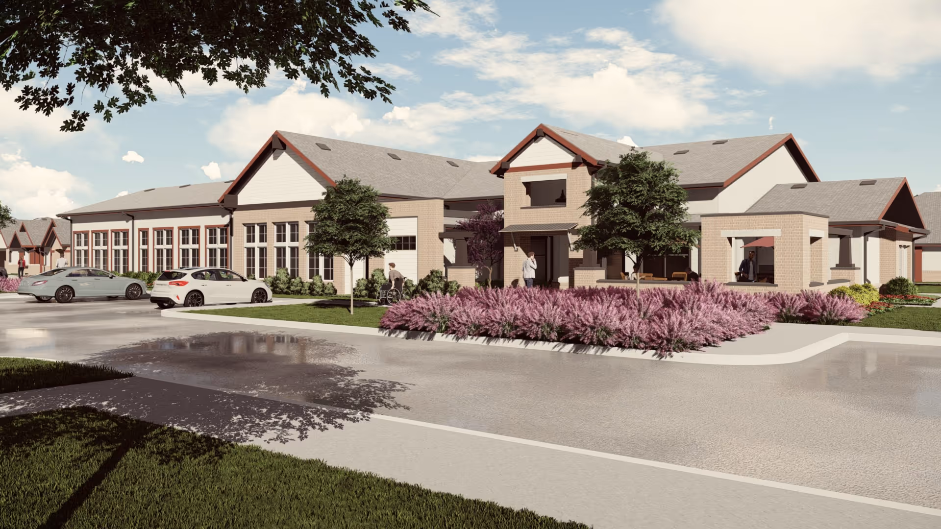 Exterior view of Woodland Cottages Senior Living College Station building with a parking area in front, landscaped with trees and purple flowering bushes, and a few people near the entrance.