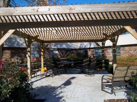 Outdoor brick courtyard with a wooden pergola, tables and chairs.