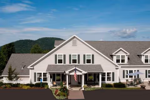 Front view of Woodstock Terrace senior living building with entrance, flag, and landscaping.