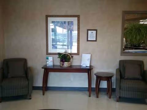 Two striped armchairs flank a wooden console table with a plant and framed art.