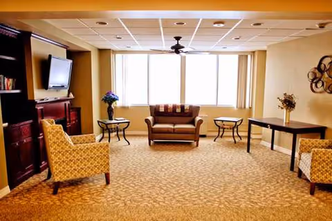 Edgerton Care Center lounge with sofas, chairs, tables, TV, and large windows.