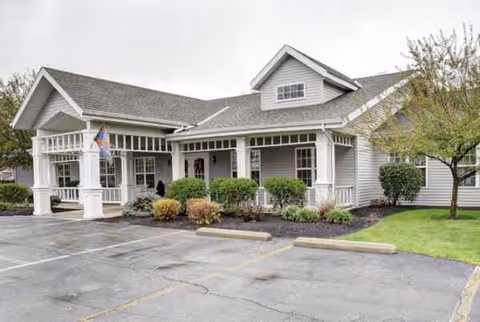 Exterior view of DeWolfe Place senior living facility with a covered entrance and landscaping.