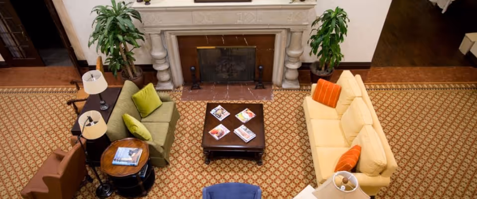 Overhead view of a furnished communal living room with sofas, a coffee table, and a fireplace.
